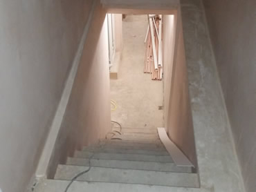basement staircase is fitted with wooden steps and plastered to the top door